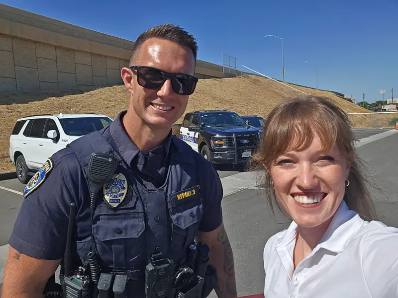 Kathryn Halling with a Bakersfield police officer beside a patrol truck